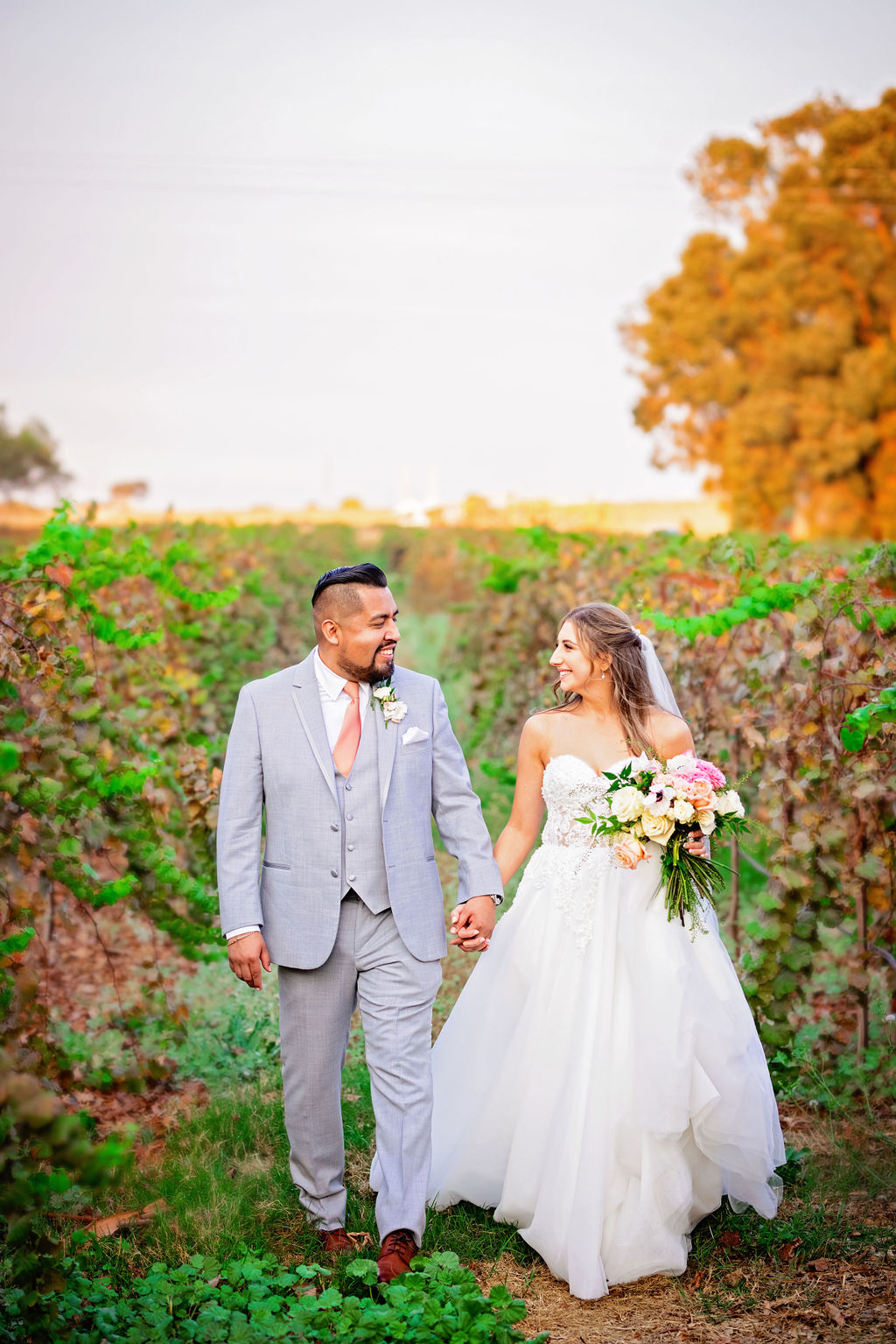 Newlyweds holding hands and walking through a vineyard at Belle Vie Vineyard