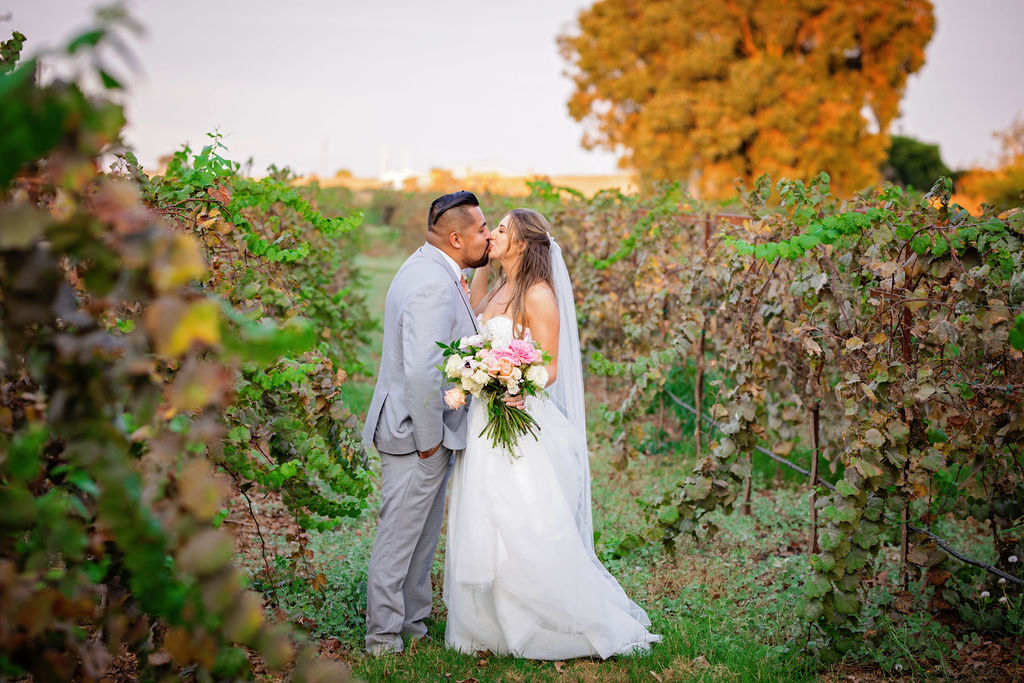 husband and wife in wedding outfits sharing a kiss in Belle Vie Vineyard