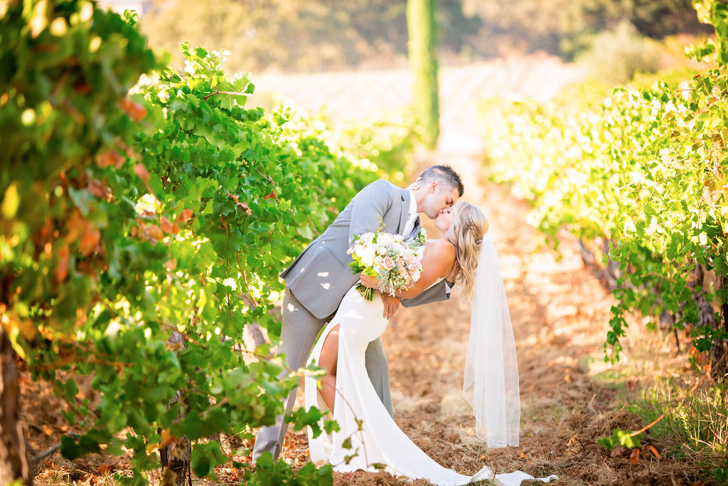 groom dipping bride to kiss her in the vineyards at Napa CA Wedding Venues 