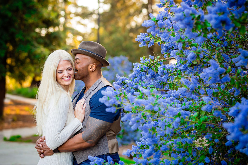 man kissing woman in the temple in a garden of blue flowers at UC Davis Arboretum Sacramento Engagement Photo Locations