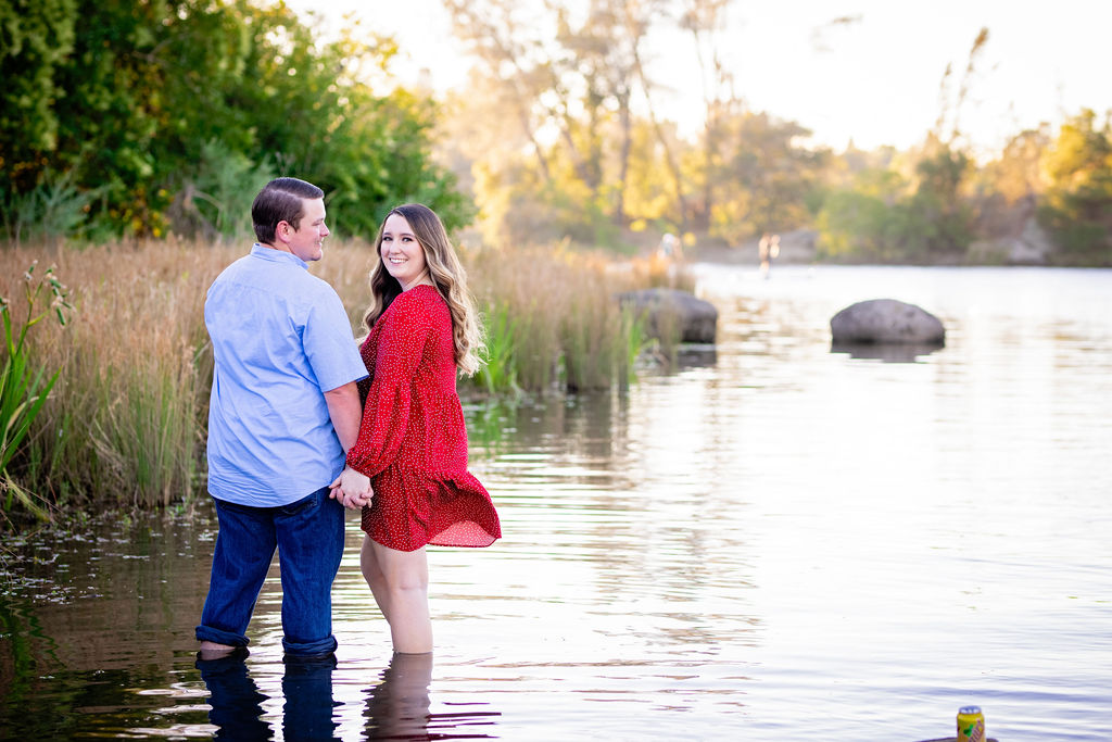 couple in red dress and blue shirt standing in Folsom Lake for Sacramento Engagement Photo Locations