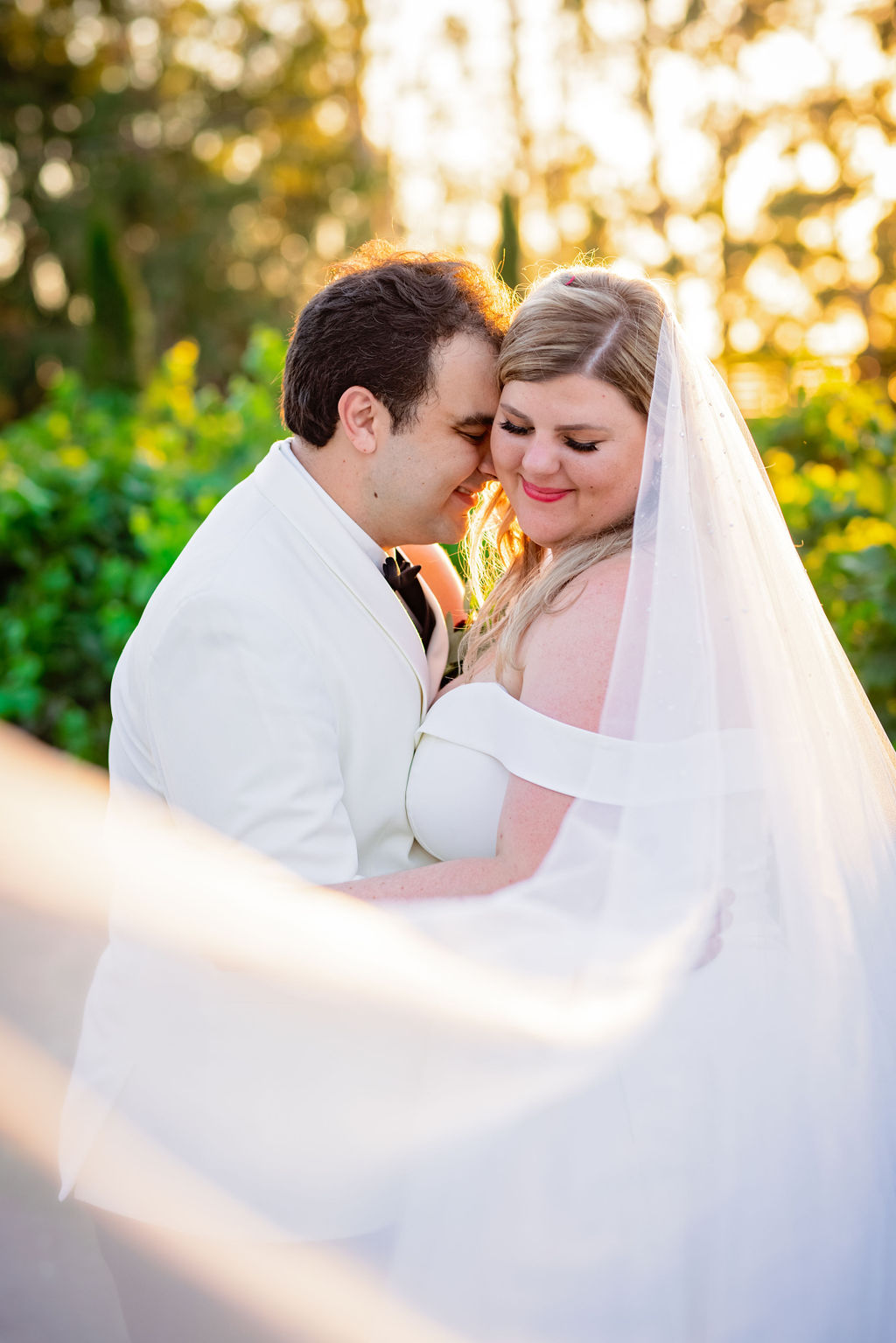 Bride and Groom nuzzling at sunset with a flowing veil at Vizcaya Sacramento