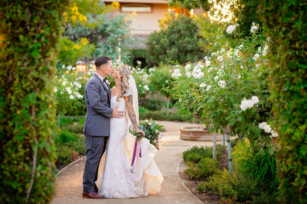 bride and groom kissing in a garden of white flowers