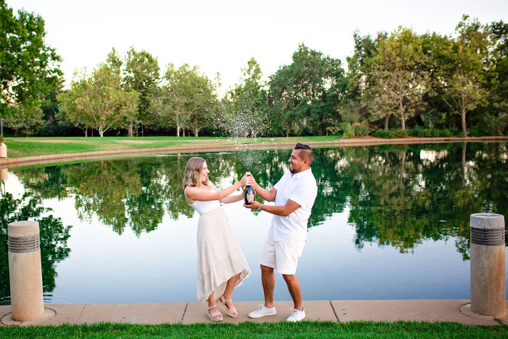 Couple popping a bottle of champagne on a lake Sacramento Bridal expo