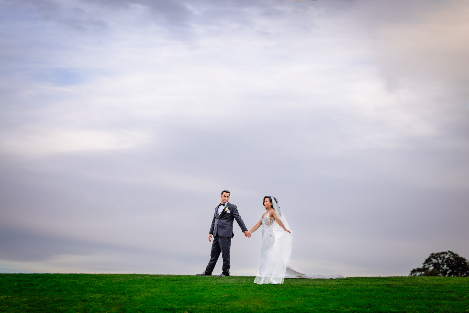 Bride and groom walk hand in hand on top of green at chico wedding venue 