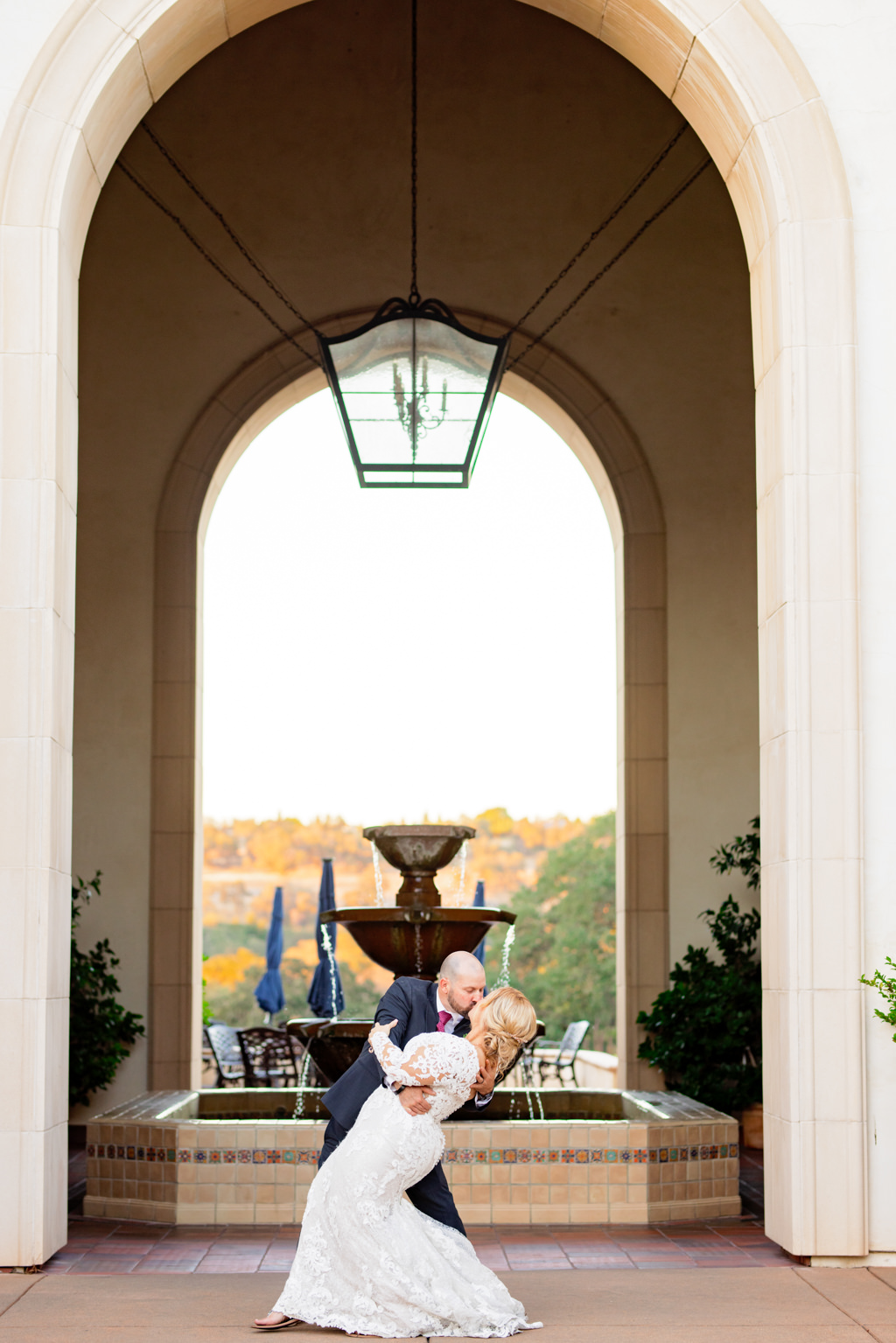 Groom dipping bride for a kiss in front of the fountain at their catta verdera wedding