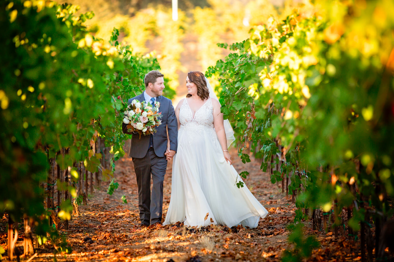 bride and groom walking through the vineyards at their rancho victoria wedding